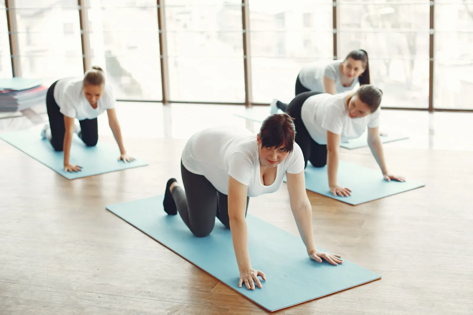 Pilatesworkout Gruppenkurs – Rückbildung in Köln Frauen im Vierfüßlerstand auf Gymnastikmatten beim Pilatesworkout in der Gruppe, wie es zur Rückbildung und Körperwahrnehmung eingesetzt wird